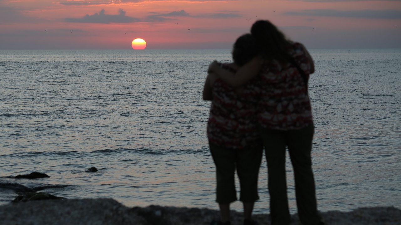 Two people hug as the sun sets.
